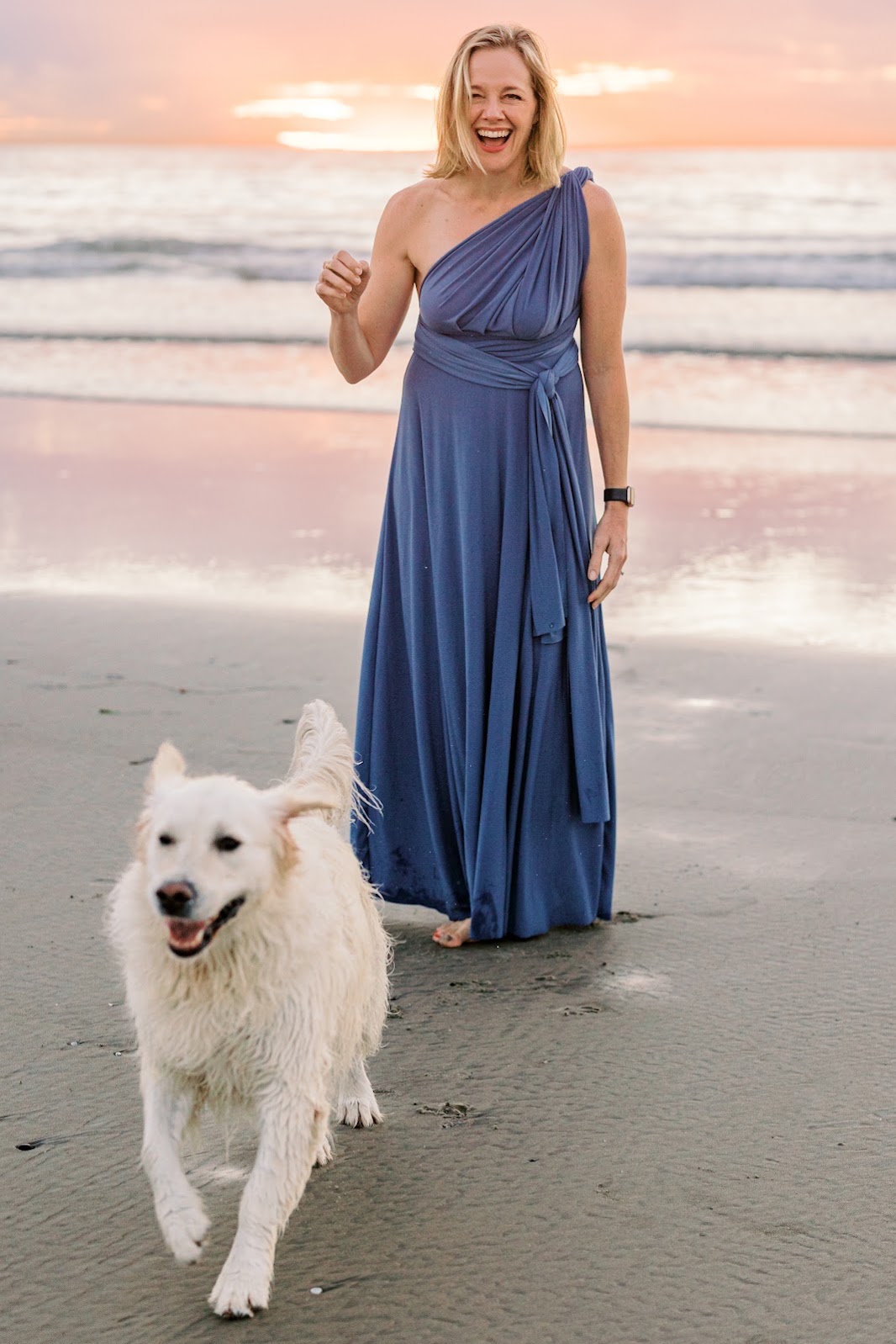 Susan laughing on the beach at sunset with her dog Aerobie